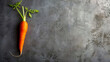 Fresh carrot with green leaves on a dark, textured surface.