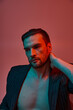 © LIGHTFIELD STUDIOS - portrait of man with bare chest posing in elegant pinstripe suit in studio with red and blue light