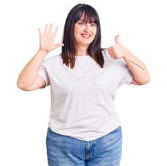 Wall Mural - Young plus size woman wearing casual clothes showing and pointing up with fingers number six while smiling confident and happy.