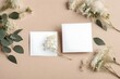 Wedding invitation card mockup with natural eucalyptus and white gypsophila twigs. Blank card mockup on beige background. realistic HD .