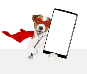 Aufkleber - jack russell terrier wearing like a doctor with superhero cape and with stethoscope on his neck shows big smartphone with white blank screen in it paw above empty banner. Isolated on white background