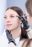 Fototapeta Zwierzęta - Teen girl having Eyebrow coloring procedure at beauty salon. Professional beauty care concept. Beauty master coloring eyebrow is working