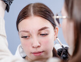 Fototapeta Zwierzęta - Teen girl having Eyebrow coloring procedure at beauty salon. Professional beauty care concept. Beauty master coloring eyebrow is working
