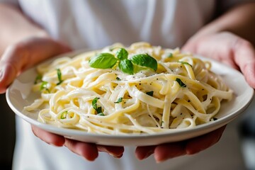 Poster - Closeup of hands holding a plate of pasta topped with basil leaves
