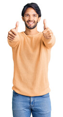 Canvas Print - Handsome hispanic man wearing casual sweater approving doing positive gesture with hand, thumbs up smiling and happy for success. winner gesture.