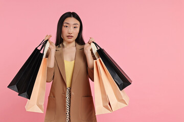 Poster - Beautiful woman with shopping bags on pink background. Space for text