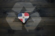 wooden heart with national flag of dominican republic near reduce, reuse and recycle sing on the wooden background.concept