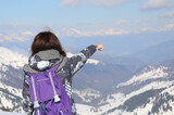 Fototapeta Boho - girl hiker during the trip  in winter with the purple backpack on her shoulders points to a point on the horizon
