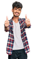 Wall Mural - Young hispanic man wearing casual clothes approving doing positive gesture with hand, thumbs up smiling and happy for success. winner gesture.