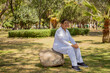 Serene Afternoon With an Elderly  Woman Seated on a Park Boulder in Casual White Clothing