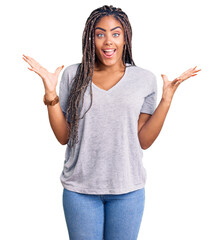 Wall Mural - Young african american woman with braids wearing casual clothes celebrating victory with happy smile and winner expression with raised hands