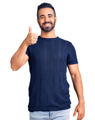 Canvas Print - Young hispanic man wearing casual clothes smiling happy and positive, thumb up doing excellent and approval sign