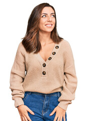 Wall Mural - Young brunette woman wearing casual winter sweater looking away to side with smile on face, natural expression. laughing confident.