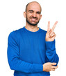 © Krakenimages.com - Young hispanic man wearing casual clothes smiling with happy face winking at the camera doing victory sign. number two.