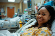 African-American woman patient hospitalized smiling on a hospital stretcher in the background. Postoperative and healthcare concept.