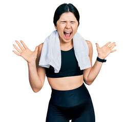 Wall Mural - Young brunette woman with blue eyes wearing sportswear and towel celebrating mad and crazy for success with arms raised and closed eyes screaming excited. winner concept