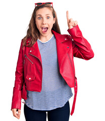 Canvas Print - Young beautiful blonde woman wearing casual leather jacket pointing finger up with successful idea. exited and happy. number one.