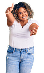 Wall Mural - Young african american plus size woman wearing casual clothes looking at the camera smiling with open arms for hug. cheerful expression embracing happiness.