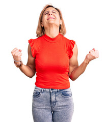 Wall Mural - Young blonde woman wearing casual clothes excited for success with arms raised and eyes closed celebrating victory smiling. winner concept.