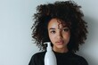 Young girl with curly hair holding a bottle of shampoo for beauty product promotion: Close-up shot. Concept Beauty Product Promotion, Curly Hair, Close-up Shot, Young Girl, Shampoo Bottle