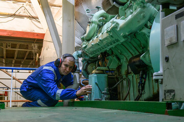 Wall Mural - Marine Engineer in blue overall working in Engine room of ship. Work at sea. Motorman.