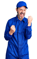 Canvas Print - Middle age handsome man wearing mechanic uniform celebrating surprised and amazed for success with arms raised and eyes closed. winner concept.