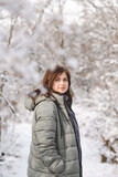 Fototapeta Koty - pretty young woman in winter clothes among trees covered with snow, girl walking in snowy forest enjoying nature