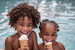 Dos niños juntos dentro del agua en la piscina sonriendo y comiendo un helado. Niños afroamericanos sonriendo dentro de la piscina.