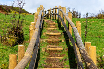 Wooden footbridge winding through sulfur fumaroles in Terceira Island's furnas, Azores.