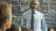 © Studio Nova - A seasoned educator discusses complex topics with students in front of a chalkboard filled with formulas.