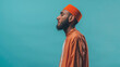 A praying Muslim is dressed in a traditional orange long-sleeved tunic with a red taqiya (prayer cap) on his head, symbolizing tradition and faith. The concept of Muslim traditions. a  copy space