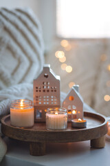 Wall Mural - Winter home aromatherapy, cozy atmosphere. Burning aroma candles on wooden tray, knitted blanket. Christmas scent, elegant interior design. Relaxation, detention, meditation, cosiness