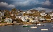 Lobster boats anchored in Stonington bay, Maine, with New England style houses on the shore in the background.