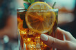 a hand holding a refreshing glass of iced tea, garnished with lemon slices and sprigs of mint, a cool and invigorating beverage enjoyed by city dwellers seeking respite from the summer heat