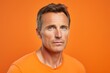 Portrait of a handsome mature man looking at the camera on an orange background