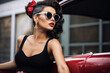 Stylish woman in retro fashion posing with a vintage convertible car