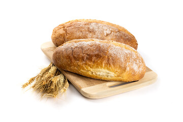 Two whole loaves of artisanal crusty bread on a wooden cutting board with a sheaf of wheat isolated on white