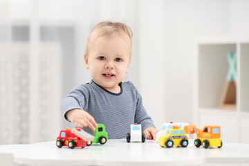 Sticker - Children toys. Cute little boy playing with toy cars at white table in room