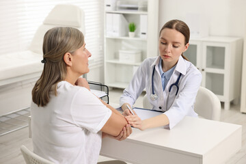 Sticker - Arthritis symptoms. Doctor examining patient's elbow in hospital