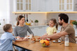 © New Africa - Happy family having breakfast at table in kitchen