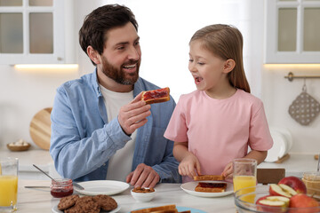 Poster - Father and his cute little daughter having breakfast at table in kitchen