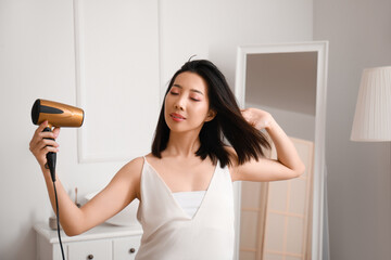 Poster - Pretty young Asian woman drying hair in bathroom