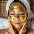 Young Asian woman masks her face with a gold facial mask. Precious metal strengthens elastin, fight free radicals  and stimulates blood circulation for firm, even, and radiant skin.