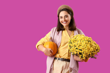 Wall Mural - Young woman with chrysanthemum flowers and pumpkin on purple background