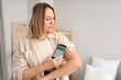 © Pixel-Shot - Diabetic woman with glucose sensor using mobile phone for measuring blood sugar level in bedroom