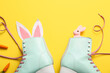 Vintage roller skates with bunny ears made of paper and carrots on yellow background. Easter celebration