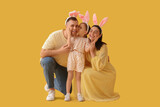 Fototapeta Dmuchawce - Happy family in Easter bunny ears on yellow background
