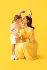 Wall Mural - Little girl with her mother in bunny ears with Easter gift on yellow background