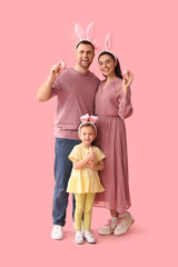 Wall Mural - Happy family in bunny ears holding Easter eggs on pink background