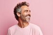 Portrait of a happy middle-aged man laughing against pink background